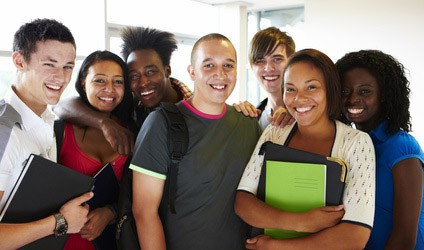 A group of adolescents smiling with backpacks and folders