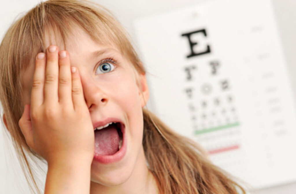 Child covering her eye to take a vision test